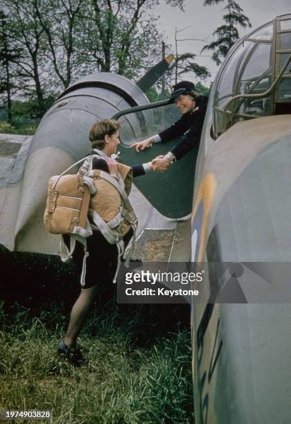 British Air Transport Auxiliary pilot Gabrielle Patterson lends a hand to British ATA pilot Jennie Broad , carrying parachutes over her shoulder, her...