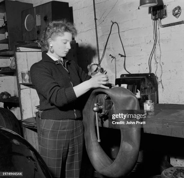 Teenage mechanic Pat Barton repairing the inner tube of a tyre at a garage in East Molesey, Surrey, England, 1955.