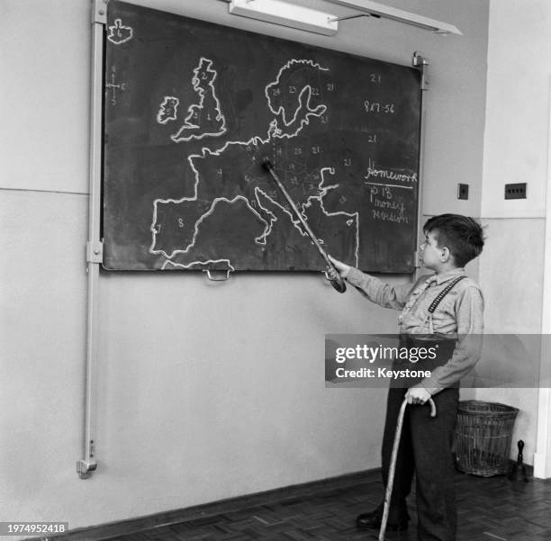 Schoolboy Douglas Miller uses a walking stick for support as he points to West Germany on a map drawn on a chalkboard at Coney Hill School, a...