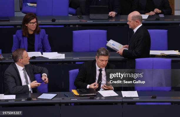 German Chancellor Olaf Scholz walks past Finance Minister Christian Lindner and Economy and Climate Action Minister Robert Habeck during debates...