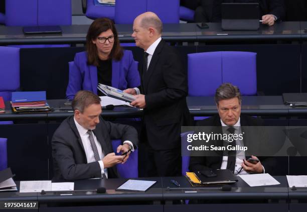 German Chancellor Olaf Scholz walks past Finance Minister Christian Lindner and Economy and Climate Action Minister Robert Habeck during debates...