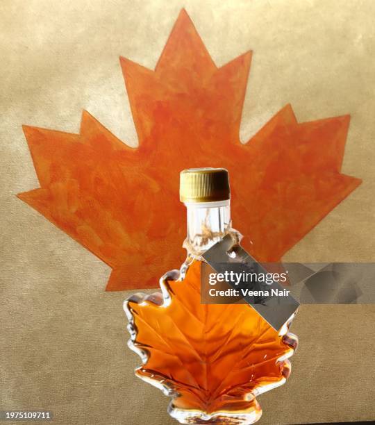 maple syrup in a maple leaf shape bottle with handwritten tag/maple leaf background - maple syrup stock pictures, royalty-free photos & images