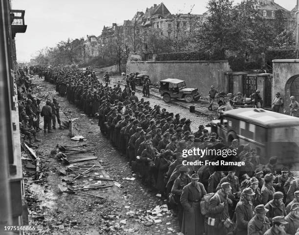 Column of German soldier prisoners of war from units of the Wehrmacht LXXXI Armeekorps, 7 Armee walk into captivity through the shell and bomb...