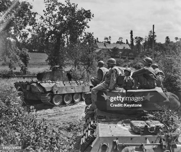 American troops riding atop a 3-inch gun motor carriage M10 Tank Destroyer from the 2nd Armored Division of VII Corps, United States First Army drive...