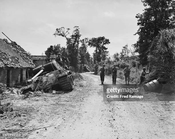 Soldiers from the 83rd Infantry Division, VIII Corps, United States First Army pass damaged and abandoned Panzerkampfwagen PzKpfw V Panther tanks of...