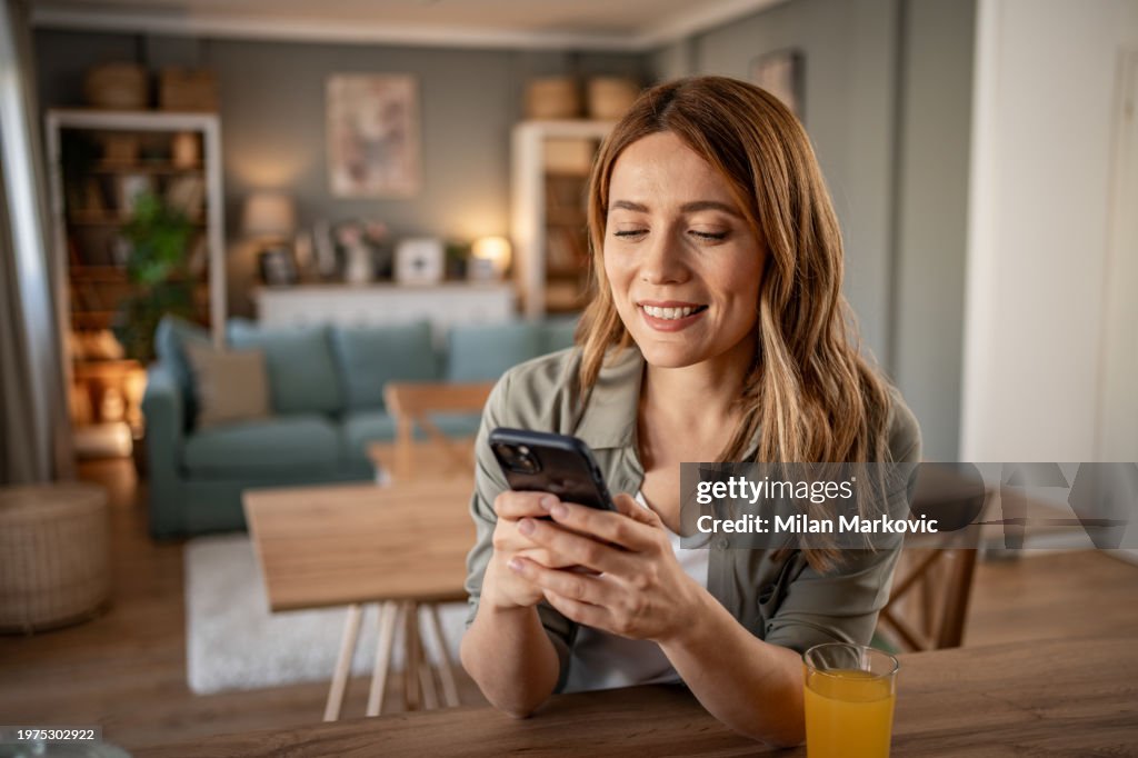 Uma jovem usa um telefone celular lendo as últimas notícias enquanto se prepara para o café da manhã