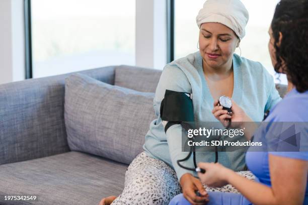mature female patient watches as the nurse completes her medical examination - hospice stock pictures, royalty-free photos & images