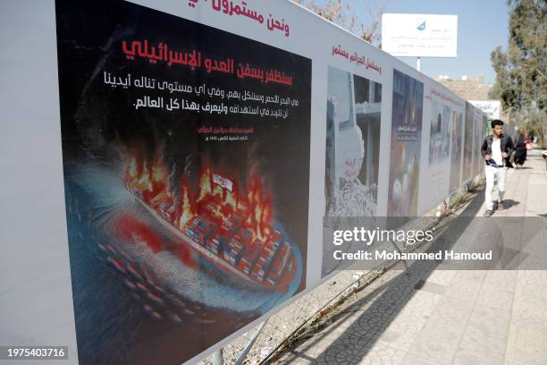 Man walks next to a billboard bearing the image of a commercial ship holding the Israeli flag as if it's burning after it was targeted by missiles in...