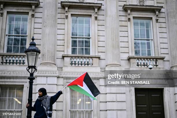 Pro-Palestinian supporter waves a Palestinian flags during a National March for Palestine in central London on February 3, 2024. Deadly strikes were...