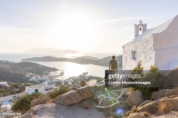 enchanting sunset stroll: a man explores the beauty of a greek village - ios grécia imagens e fotografias de stock