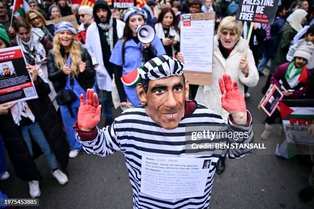 Demonstrator wearing a mask depicting Britain's Prime Minister Rishi Sunak and dressed with a prisoner uniform takes part in a National March for...