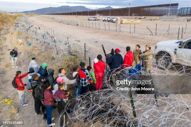 Seen from an aerial view, Texas National Guard troops stop immigrants trying to pass through razor wire after crossing the border into El Paso, Texas...