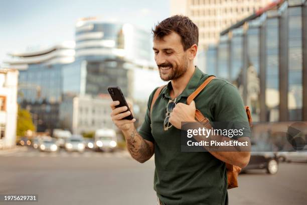 mann mit smartphone in der hand surft auf der straße in sozialen medien - mobiles gerät stock-fotos und bilder