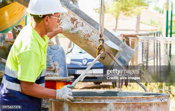 engineer standing with a conveyor belt pouring cement into a mixer for a construction site, side view - mud truck stock pictures, royalty-free photos & images