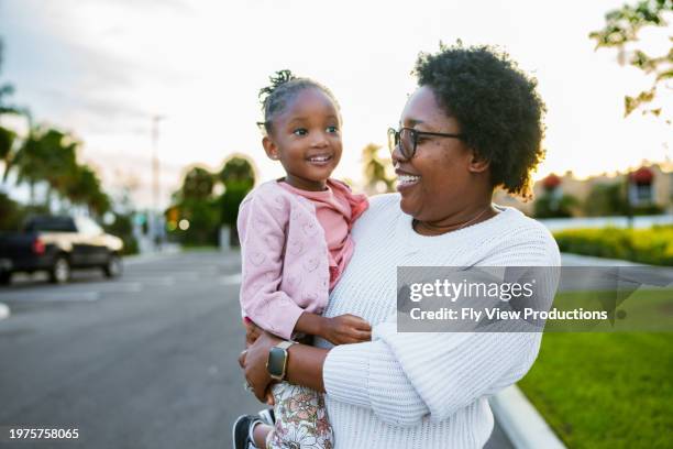 woman holds daughter while walking outside - community stock pictures, royalty-free photos & images
