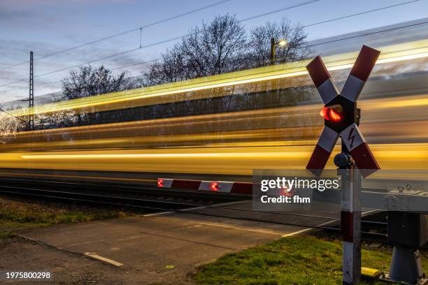 railroad crossing with fast train at night - traverser photos et images de collection