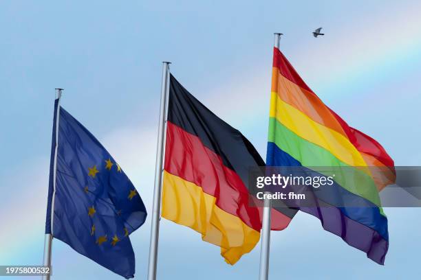 eu-, german- and rainbow(lgbtq+)- flag with rainbow in the sky - berlin gay pride stock pictures, royalty-free photos & images