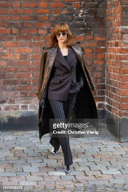 Justine Soranzo wears black striped pants, blazer, bag, brown coat, glove outside Herskind during the Copenhagen Fashion Week AW24 on January 31,...