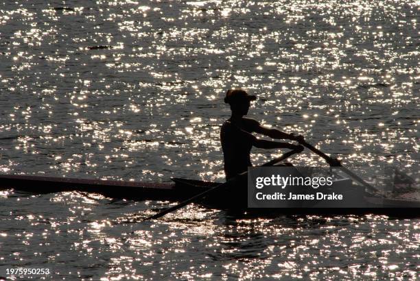 Female rower powers her scull forward on the Schuylkill River in Fairmount Park in Philadelphia, Pennsylvania near twilight in 2007.