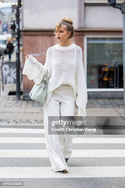 Guest wears white jumper with long sleeves, mint green Hermes bag, white pants outside The Garment during the Copenhagen Fashion Week AW24 on January...