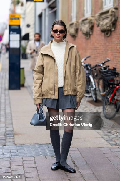 Mary L. Jean wears beige zipper jacket, grey mini skirt, tights, blue bag, knee high socks, creme white knit, sunglasses outside The Garment during...