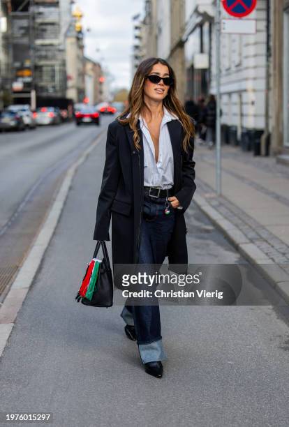 Bruna Rizik wears black jacket, dark denim jeans, Hermes bag with Palestine colors outside The Garment during the Copenhagen Fashion Week AW24 on...