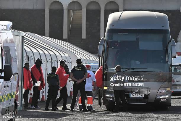 Migrants board a bus helped by members of the Spanish Red Cross and Guardia Civil officers following their rescue by the Spanish Salvamento Maritimo...