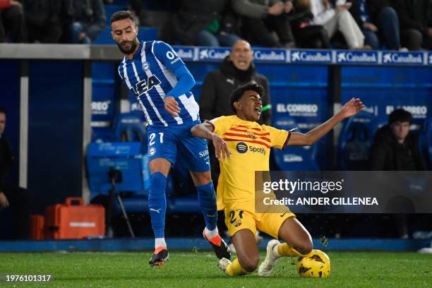 Barcelona's Spanish forward Lamine Yamal falls down next to Alaves' Algerian forward Abderrahmane Rebbach during the Spanish league football match...