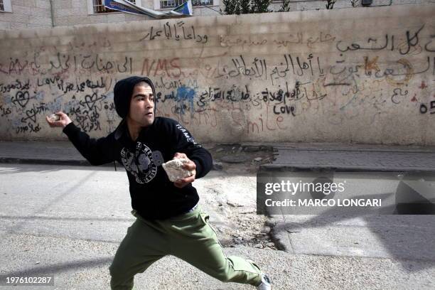 Palestinian youth gets throws a stone towards Israeli forces in the Shuafat refugee camp in Jerusalem on February 8, 2010 during an Israeli police...