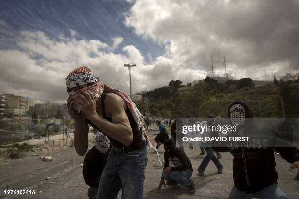 Masked Palestinian youths throw stones at Israeli soldiers in east Jerusalem on March 16, 2010. Hundreds of Palestinians clashed with Israeli...