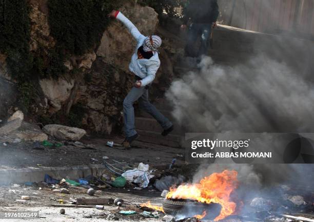Masked Palestinian youth hurls stones at Israeli soldiers during clashes in the West Bank refugee camp of Qalandia on March 18, 2010. Tensions over...