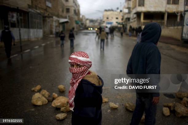 Masked Palestinian demonstrator pauses during clashes following Friday prayers in the West Bank town of Hebron on February 26, 2010. Palestinian...