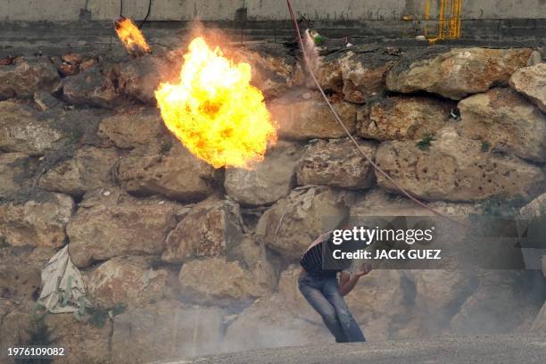 Masked Palestinian youth throws a fire bomb towards Israeli forces during clashes following Friday prayer in Arab east Jerusalem on May 13, 2011 as...