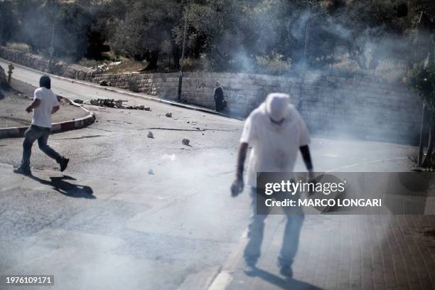 Cloud of tear gas engulfs masked Palestinians demonstrating in the flashpoint Jerusalem neighborhood of Silwan April 29, 2011 during clashes with...