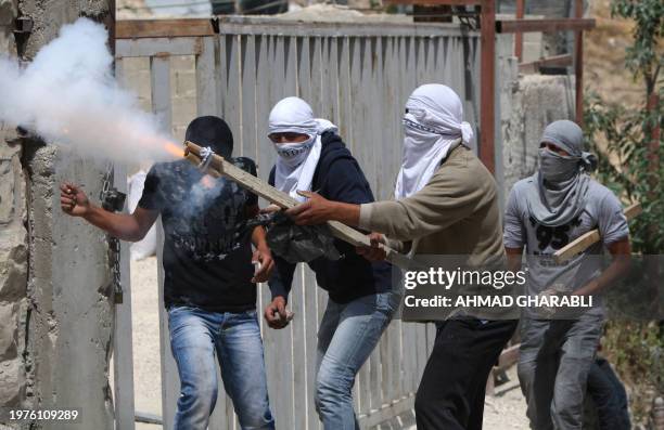 Masked Palestinian youths fire a makeshift bomb towards Israeli forces during clashes following Friday prayer in Arab east Jerusalem on May 13, 2011...