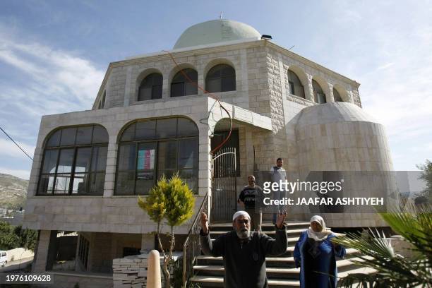Palestinians stand outside a mosque that allegedly was spray-painted with Hebrew graffiti by Jewish settlers in the village of Hawara, near the West...