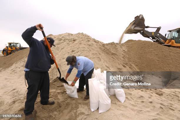 Ryan Coppenger, right, and Scott Larson, with the City of Long Beach ;Marine Bureau, collect bags of sand to be delivered to a lifeguard station that...