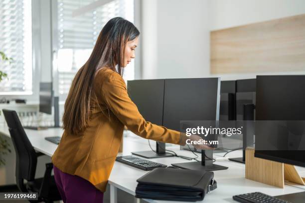femme asiatique terminant sa journée de travail au bureau - allumer photos et images de collection