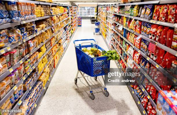 einkaufswagen in der mitte auf einem gang im supermarkt - supermarktgang stock-fotos und bilder
