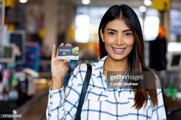 woman holding a loyalty card at a supermarket - loyalty program stock pictures, royalty-free photos & images