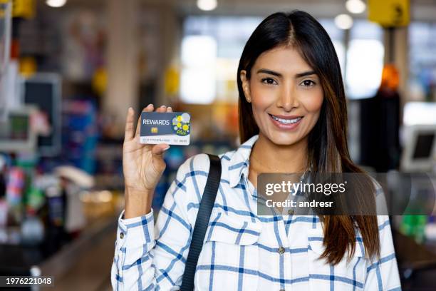 woman holding a loyalty card at a supermarket - loyalty cards stock pictures, royalty-free photos & images