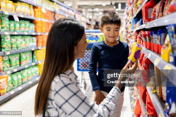 madre che permette a suo figlio di comprare un dolcetto mentre fa la spesa al supermercato - stuzzicare foto e immagini stock