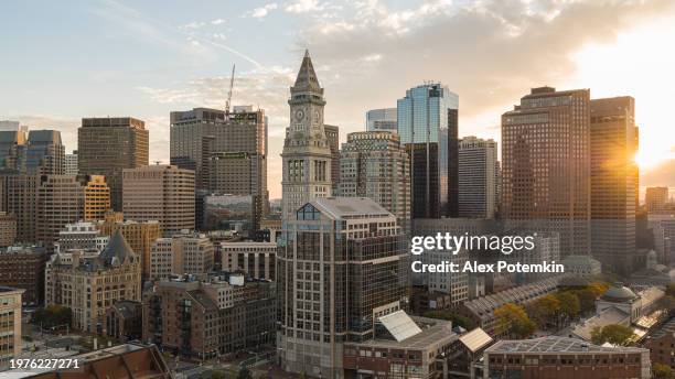 financial district of boston, massachusetts. skyscrapers skyline with famous custom house clock tower and faneuil hall in the evening with visible sunbeam. - boston vacation stock pictures, royalty-free photos & images