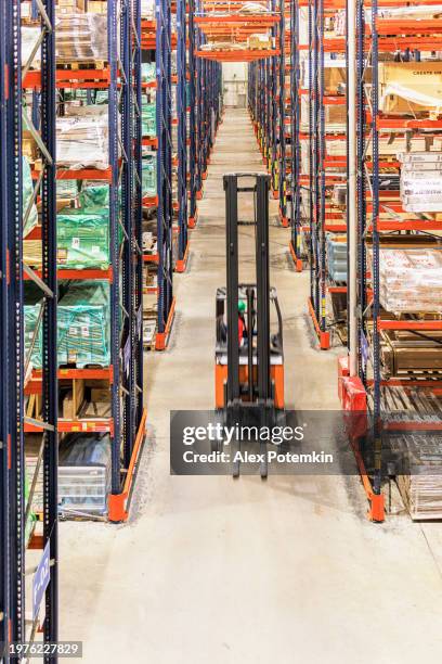 transport von waren in einem lager mit einem gabelstapler. - vertikal stock-fotos und bilder