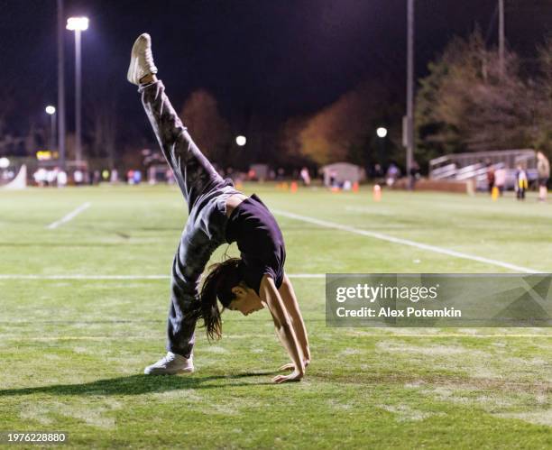 cheerleader girl practicing acrobatic exercises at the stadium in the evening. - acrobatic activity stock pictures, royalty-free photos & images