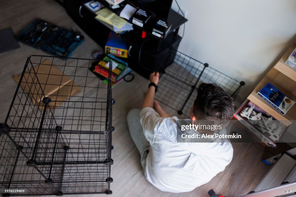 Renovation and home improvement with new furniture. Hispanic man worker making a grid shelf cabinet in new apartment. High angle