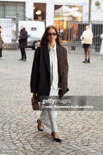 Guest wears a long silk pale blue dress and black jacket outside Herskind during the Copenhagen Fashion Week AW24 on January 31, 2024 in Copenhagen,...
