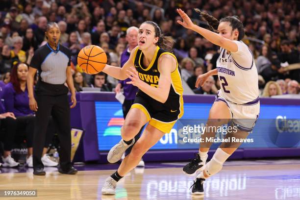 Caitlin Clark of the Iowa Hawkeyes drives to the basket against Caroline Lau of the Northwestern Wildcats during the first half at Welsh-Ryan Arena...