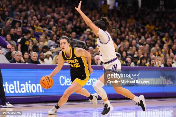 Caitlin Clark of the Iowa Hawkeyes drives to the basket against Caroline Lau of the Northwestern Wildcats during the first half at Welsh-Ryan Arena...