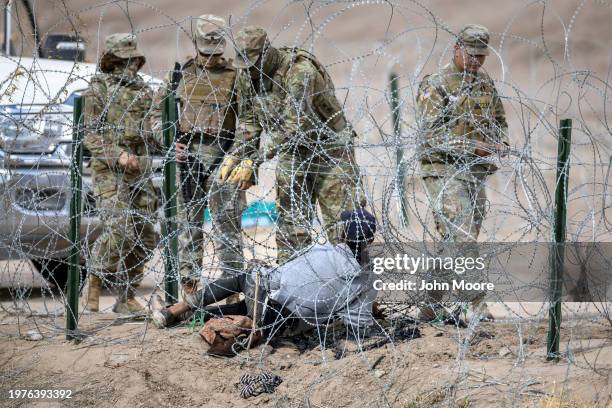 Texas National Guard troops try to untangle an immigrant caught in razor wire after he crossed the U.S.-Mexico border into El Paso, Texas on January...
